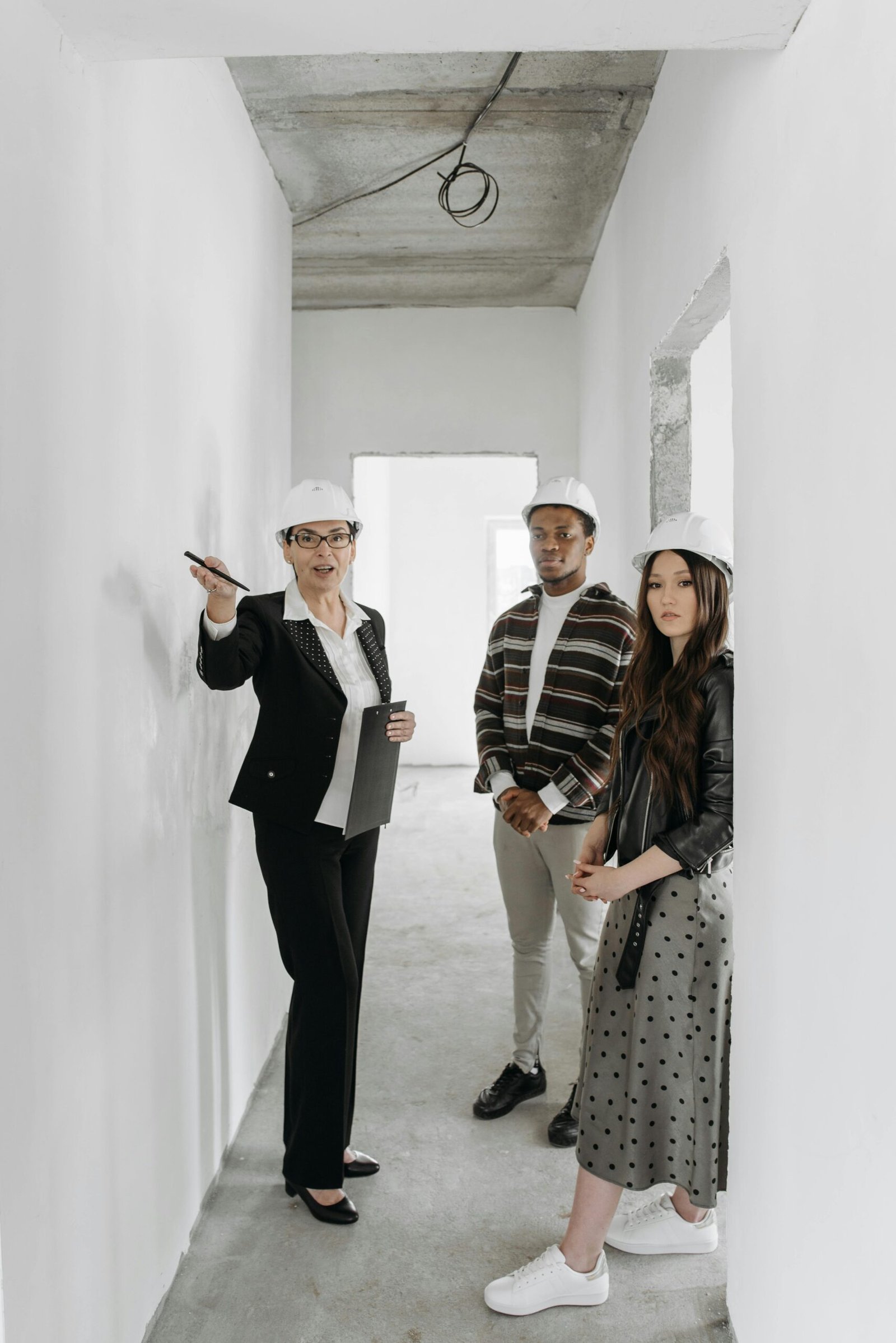 A diverse group of adults in hard hats touring a building site with a realtor.